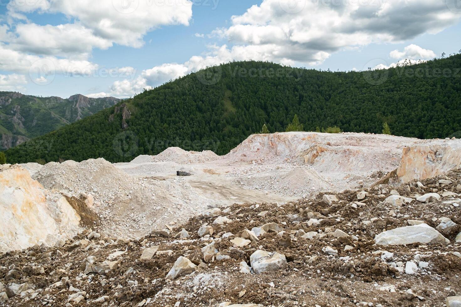 Open pit marble quarry with large piles of crushed rock and visible raw stone. photo
