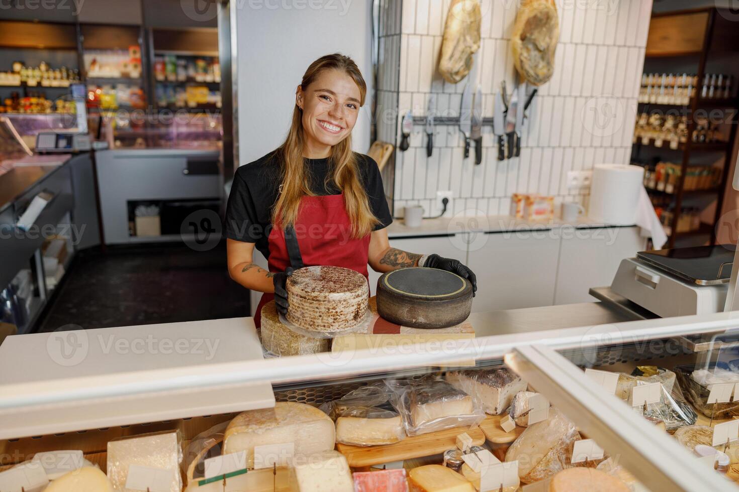 A Cheese Specialist is Smiling Joyfully Behind the Counter in a Modern Deli Environment photo