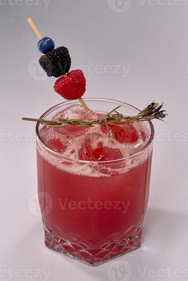 Refreshing Red Beverage Garnished with Berry Skewers and Herb Sprig Captured Against a Clean Background photo