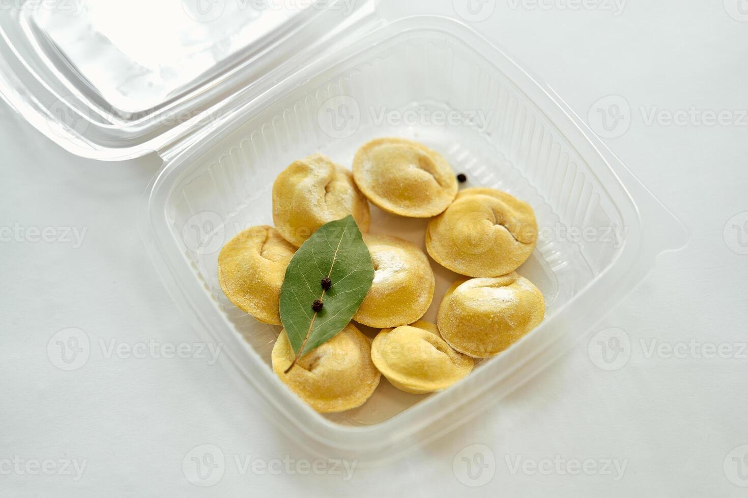 A Close-Up View of Handmade Dumplings Displayed in a Clear Container, Featuring a Preserved Bay Leaf and Spices for Culinary Presentation photo