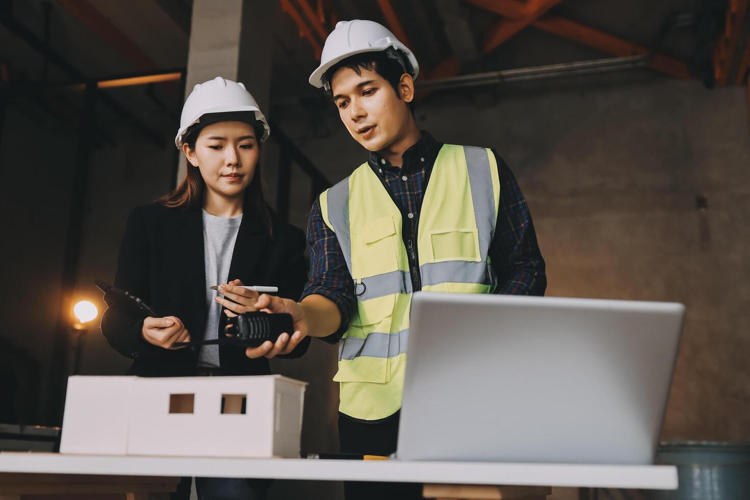 Two people in hard hats and safety vests looking at a laptop photo