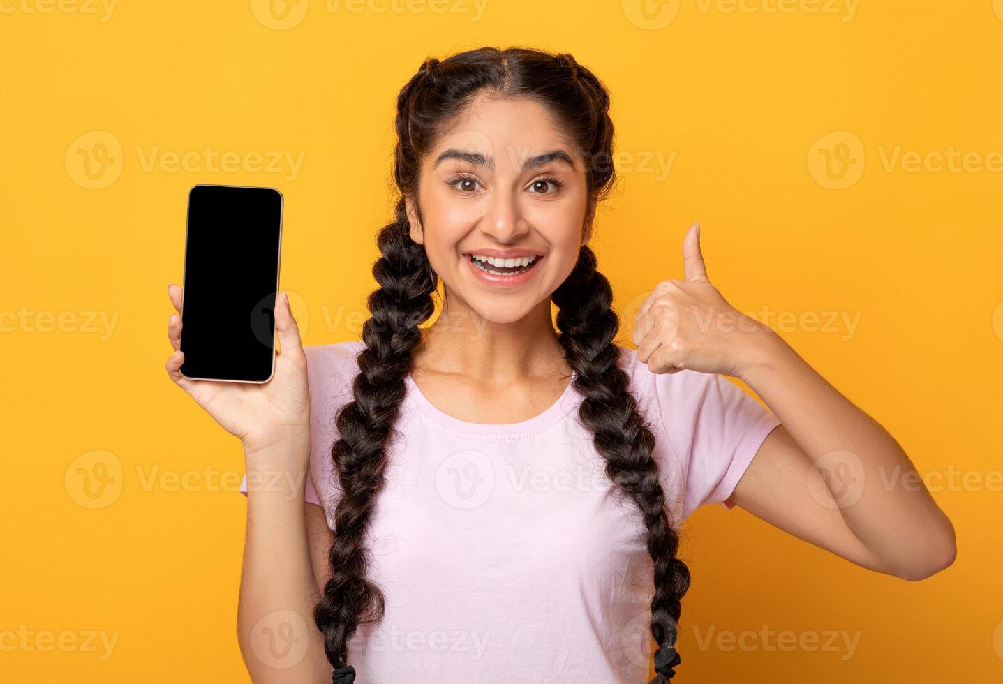 I Recommend. Portrait of excited young indian woman holding smartphone with black blank screen in hand, showing device and thumbs up sign gesture. Gadget with empty free space for mock up photo