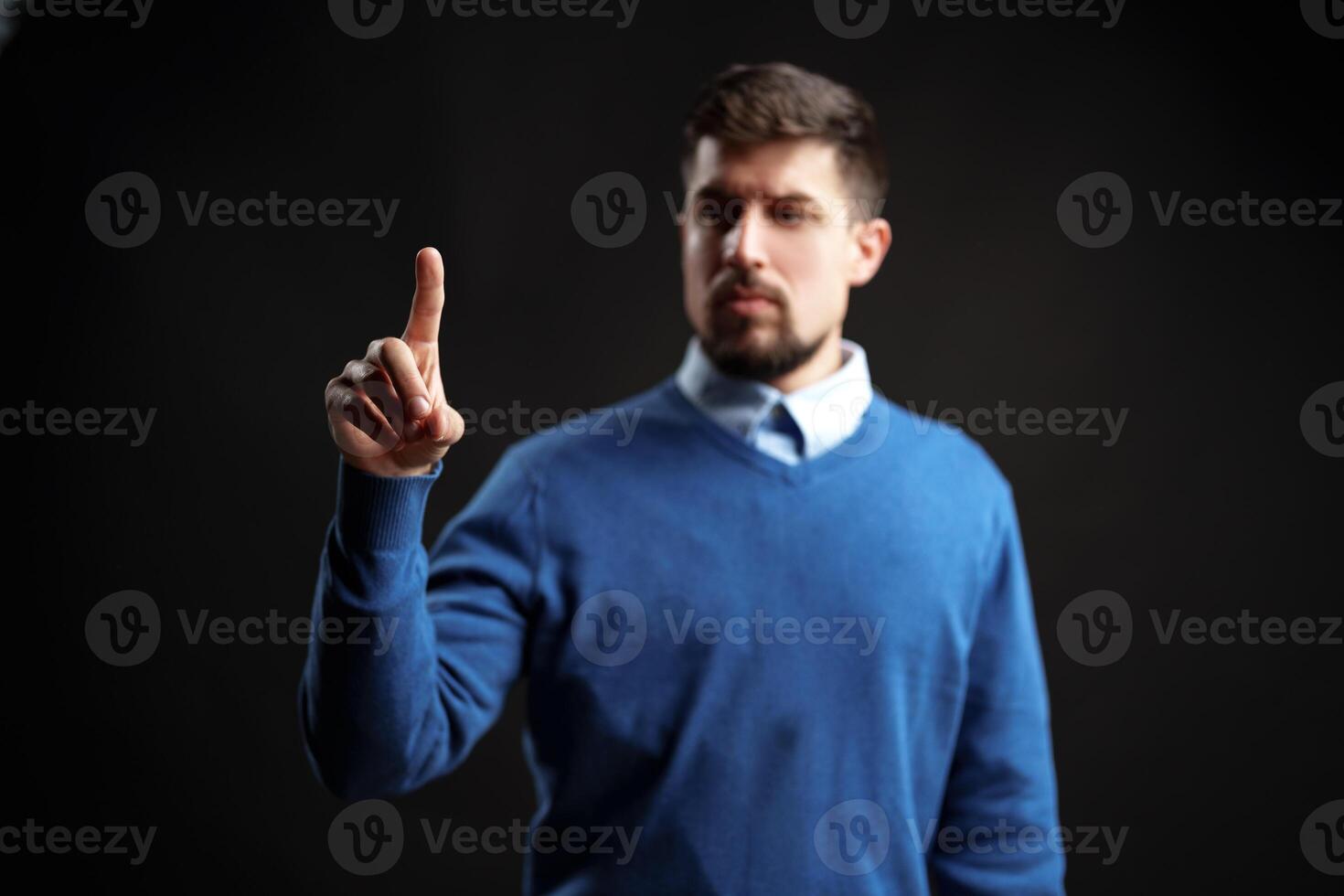 Engaging man gestures with one finger to convey a message in a dark studio setting photo