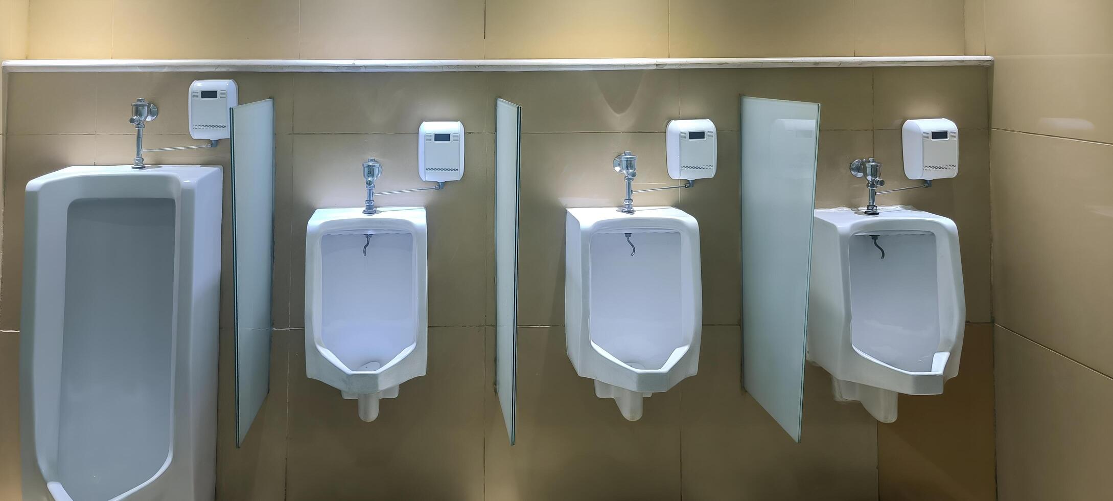 Row of modern urinals with automatic flush sensors in a public restroom. photo