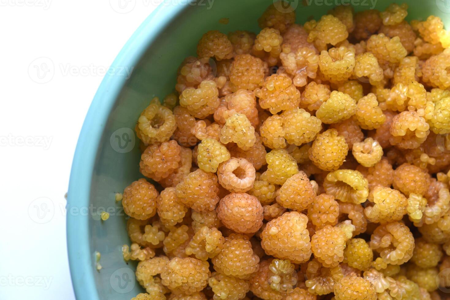 Sun-ripened yellow raspberries in a rustic bowl. Soft and aromatic. photo