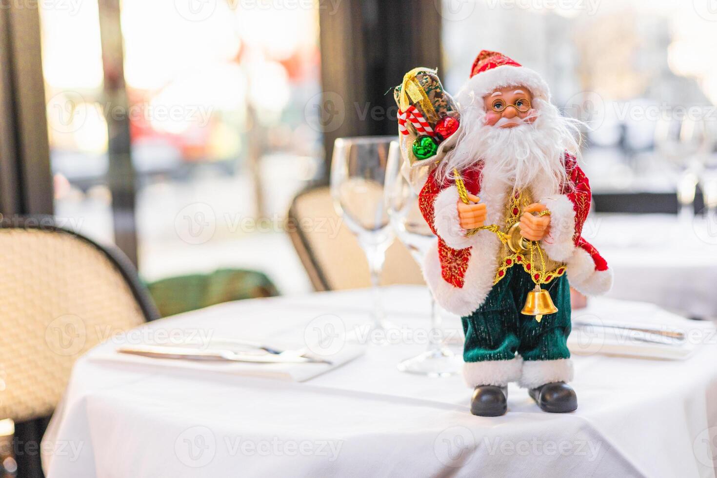 A festive table setting with decorative Santa Claus figurine. The table is elegantly arranged with glassware and cutlery, creating a cheerful holiday atmosphere. photo