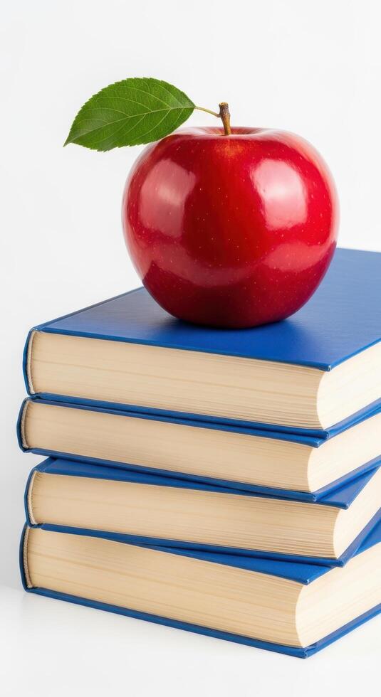 An apple sits on top of a stack of books photo