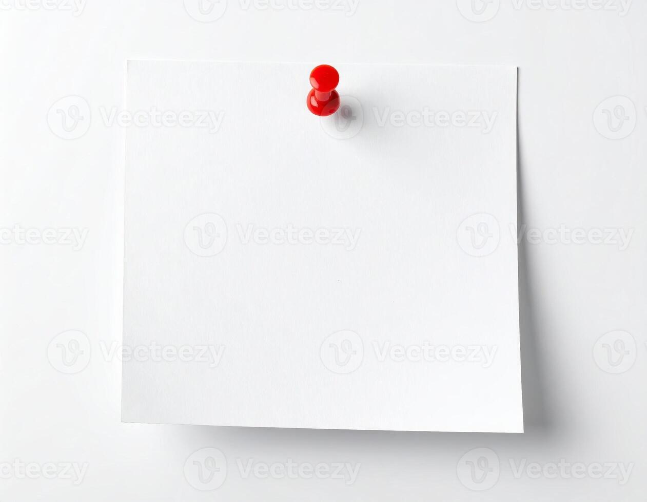 White sticky note attached with a pushpin on a plain white surface photo