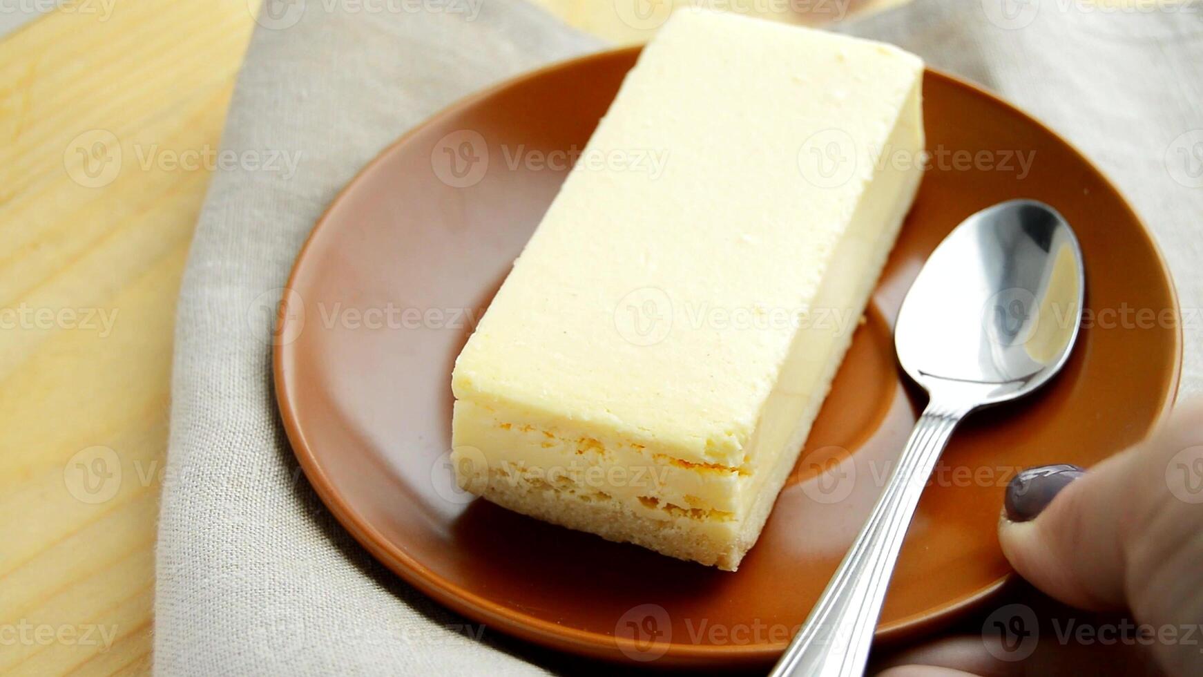 Laying out a brown plate with a rectangular slice of delicious cheesecake close-up on the table photo