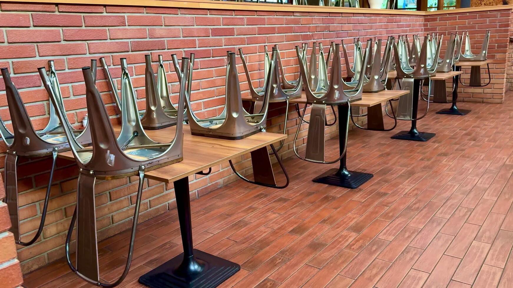 The restaurant has stacked chairs and rustic tables, creating a warm, stylish dining ambiance photo
