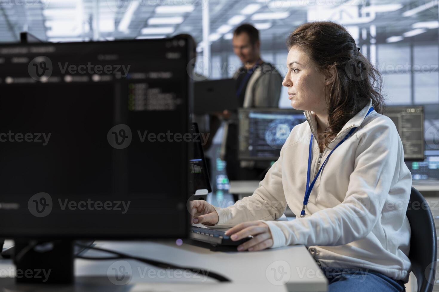 System administrator in data center coordinating deployment of server architecture, improving data processing speed. Woman in server farm configuring and testing hardware using PC photo