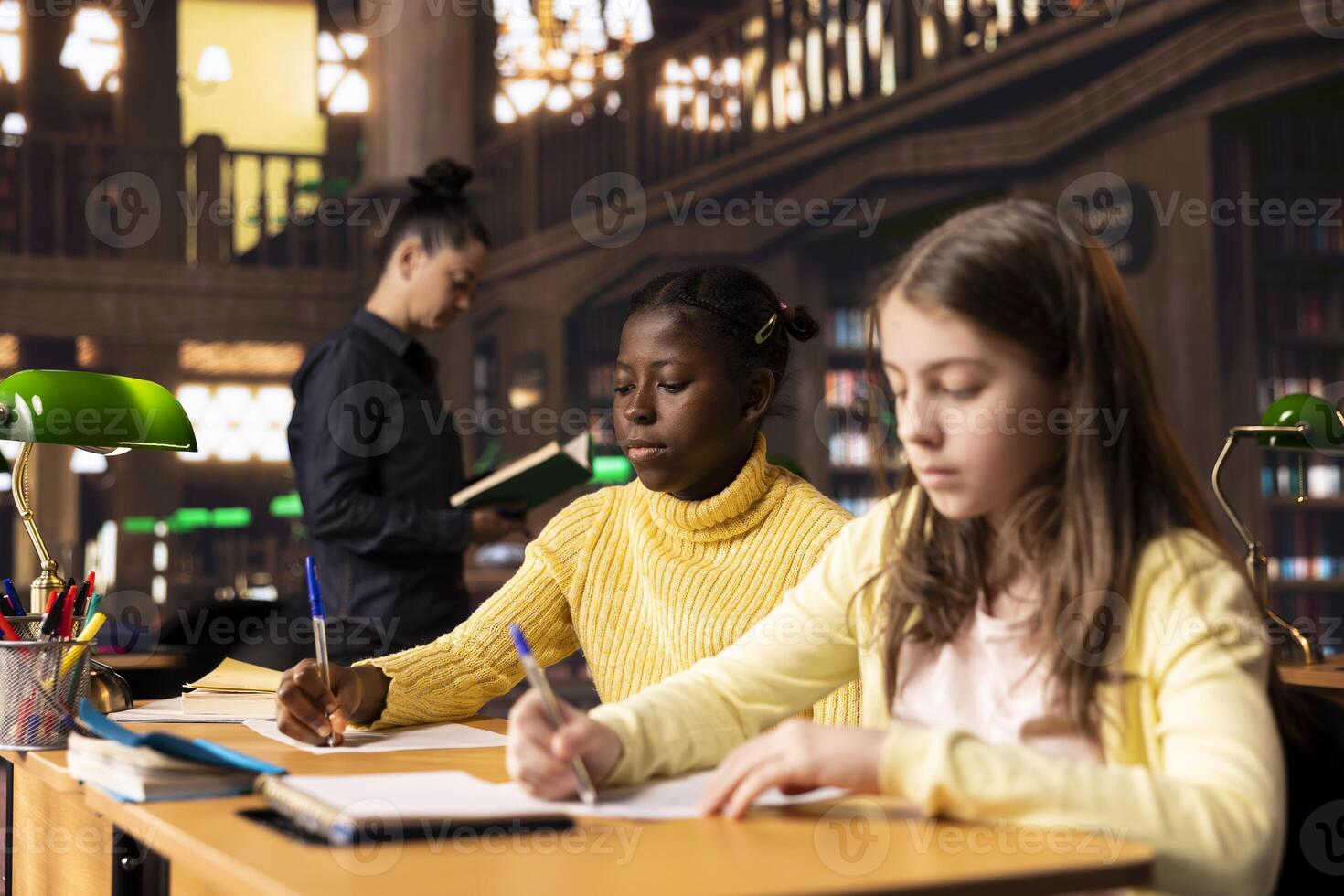 Young students filling their class notes and solving theoretical exercises in a library, showcasing positive academic development and a productive homework session. Scholars solve assignments. photo