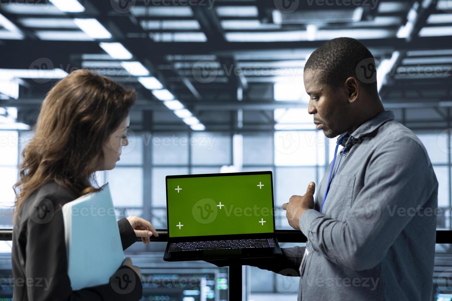 Team of engineers in data center using green screen laptop to do network virtualization. Coworkers in server farm using chroma key notebook, updating storage arrays, verifying settings photo