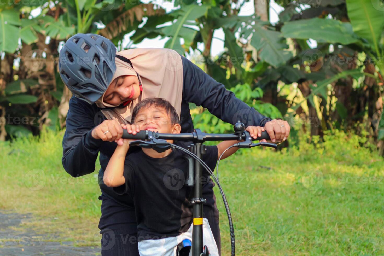 Parents and children are riding a bicycle in the park in the morning with a smiling and happy face with a tree background. with copy space photo