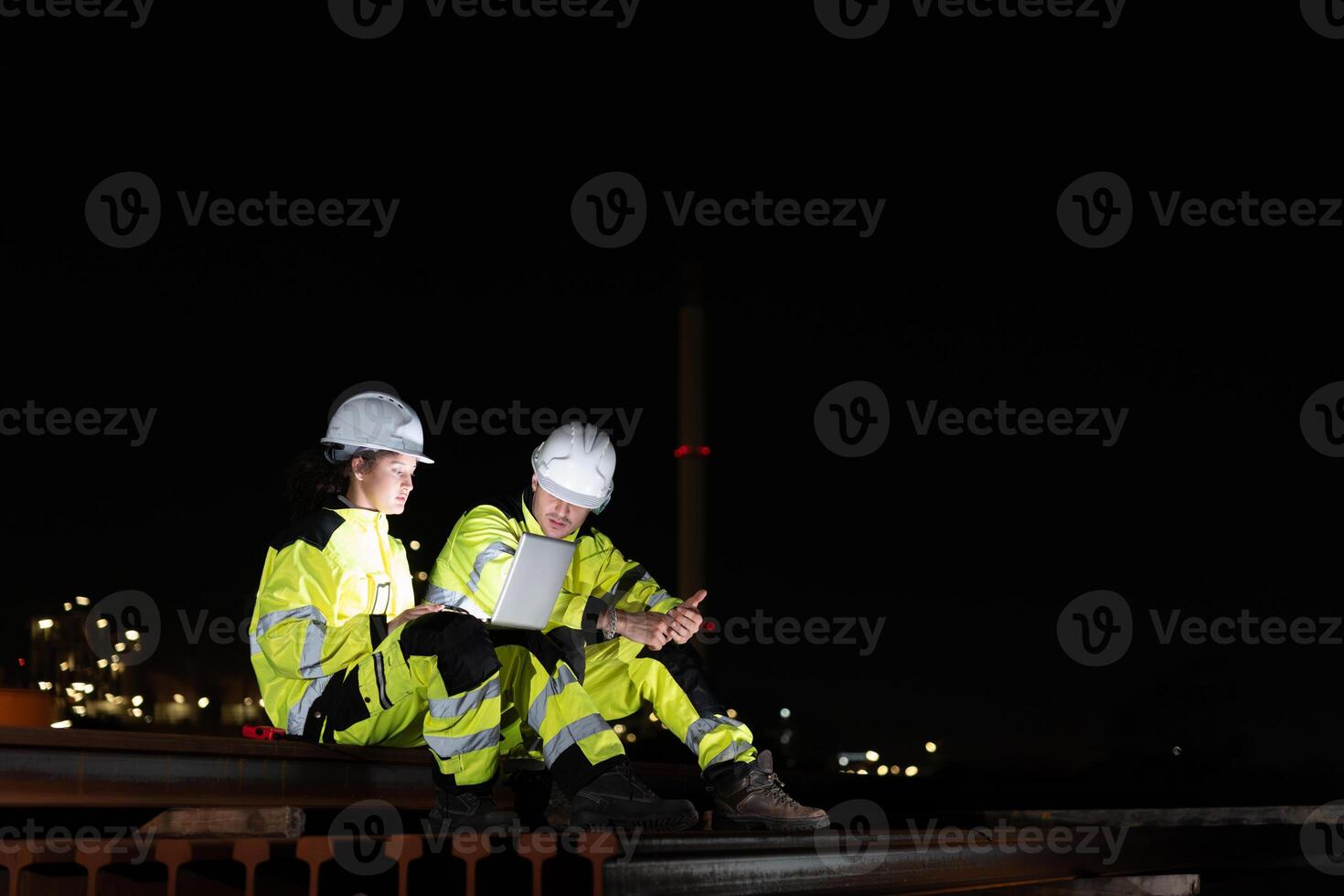 Engineers Collaborating on Site with Tablet in the Dark, Night Shift Crew Working on Industrial Project with Technology, Team of Workers Conducting Operations at Oil Storage Field Industrial Site photo