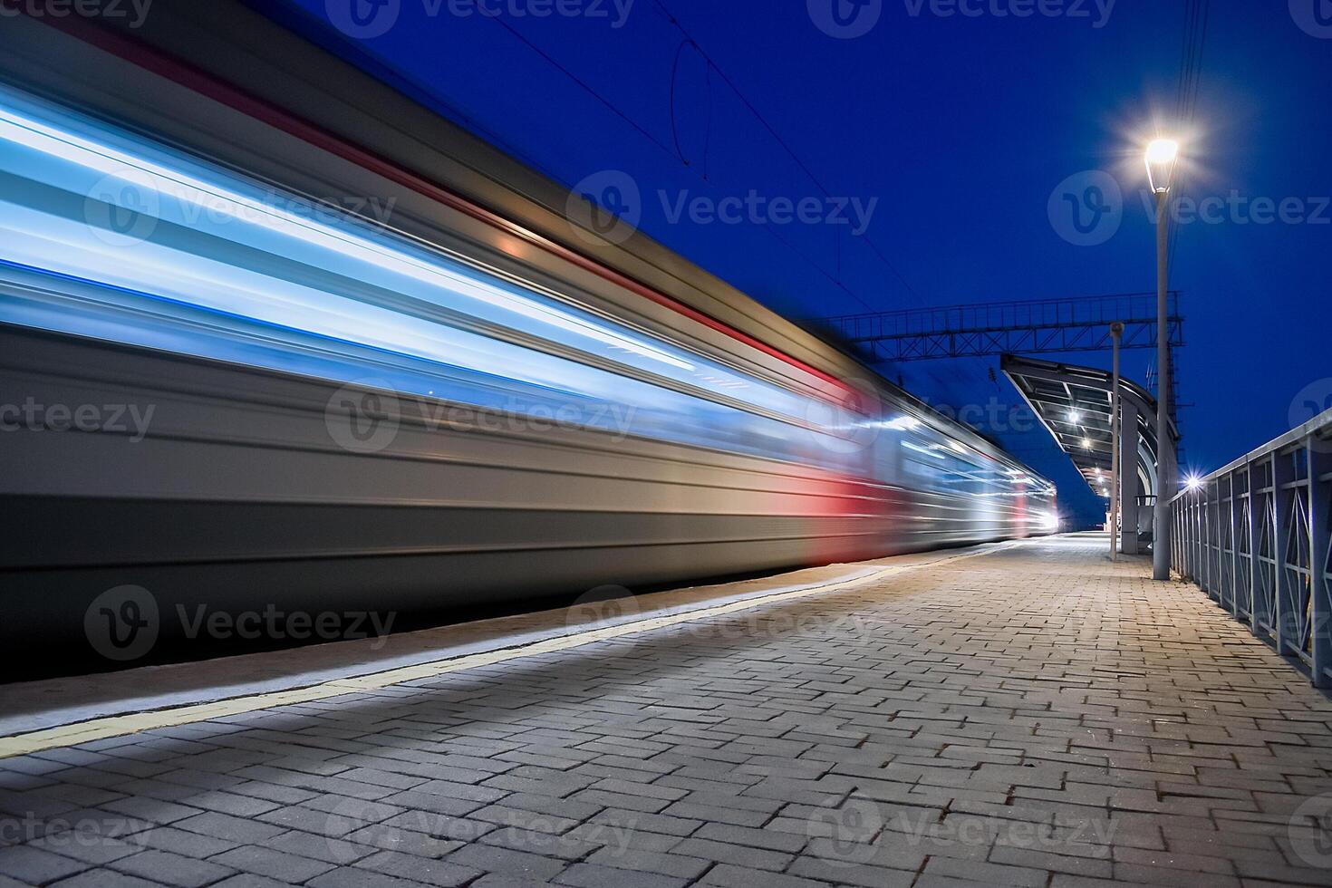 Evening arrival of the train on an empty platform..Photo taken with a shutter speed. Rays of light. Blur. Evening railway station. photo