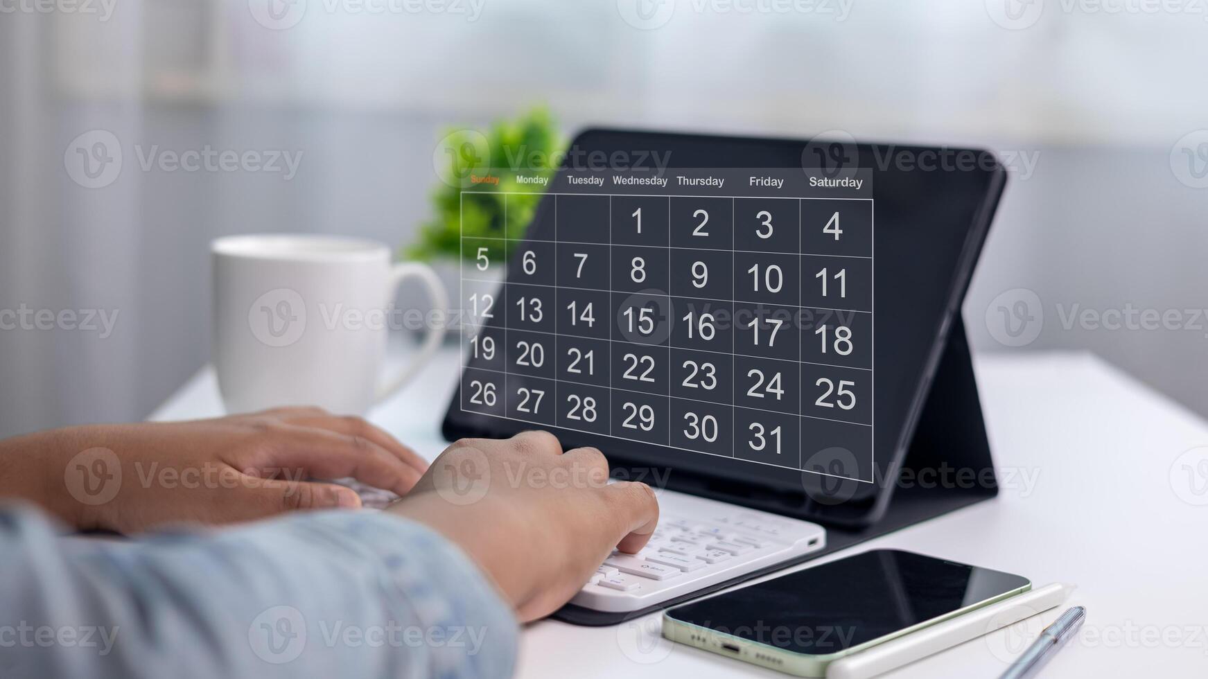 Organized person planning schedule with digital calendar app on tablet, with smartphone, keyboard, and coffee cup on modern workspace, concept of time management and productivity. photo