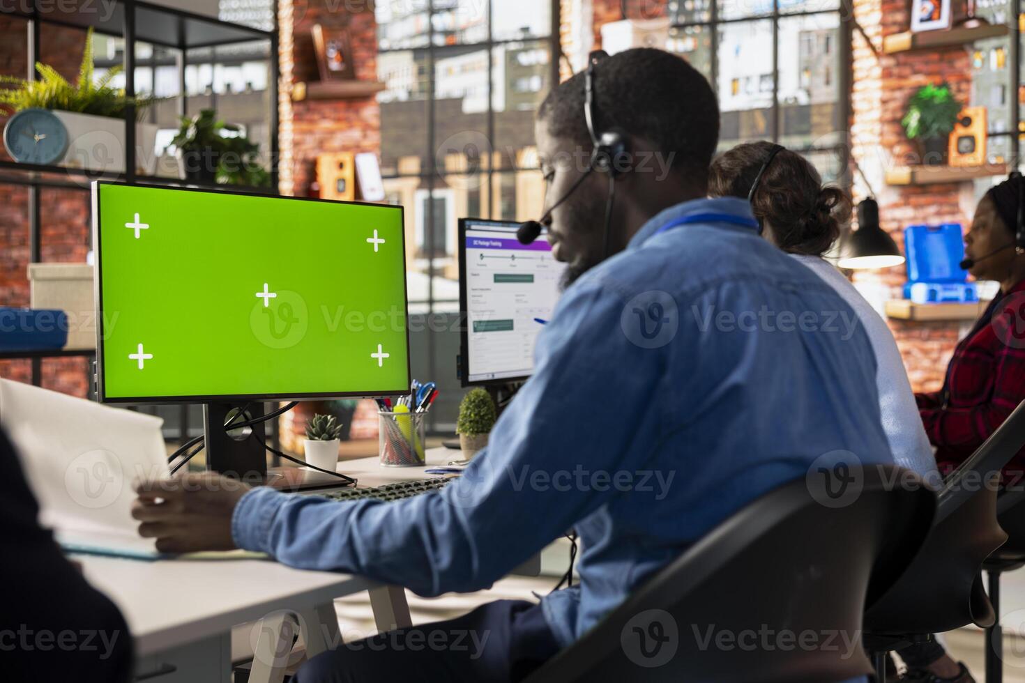 Call center admin at green screen PC desk reading paperwork, learning to improve customer loyalty. Customer support worker using mockup computer, looking over documentation photo