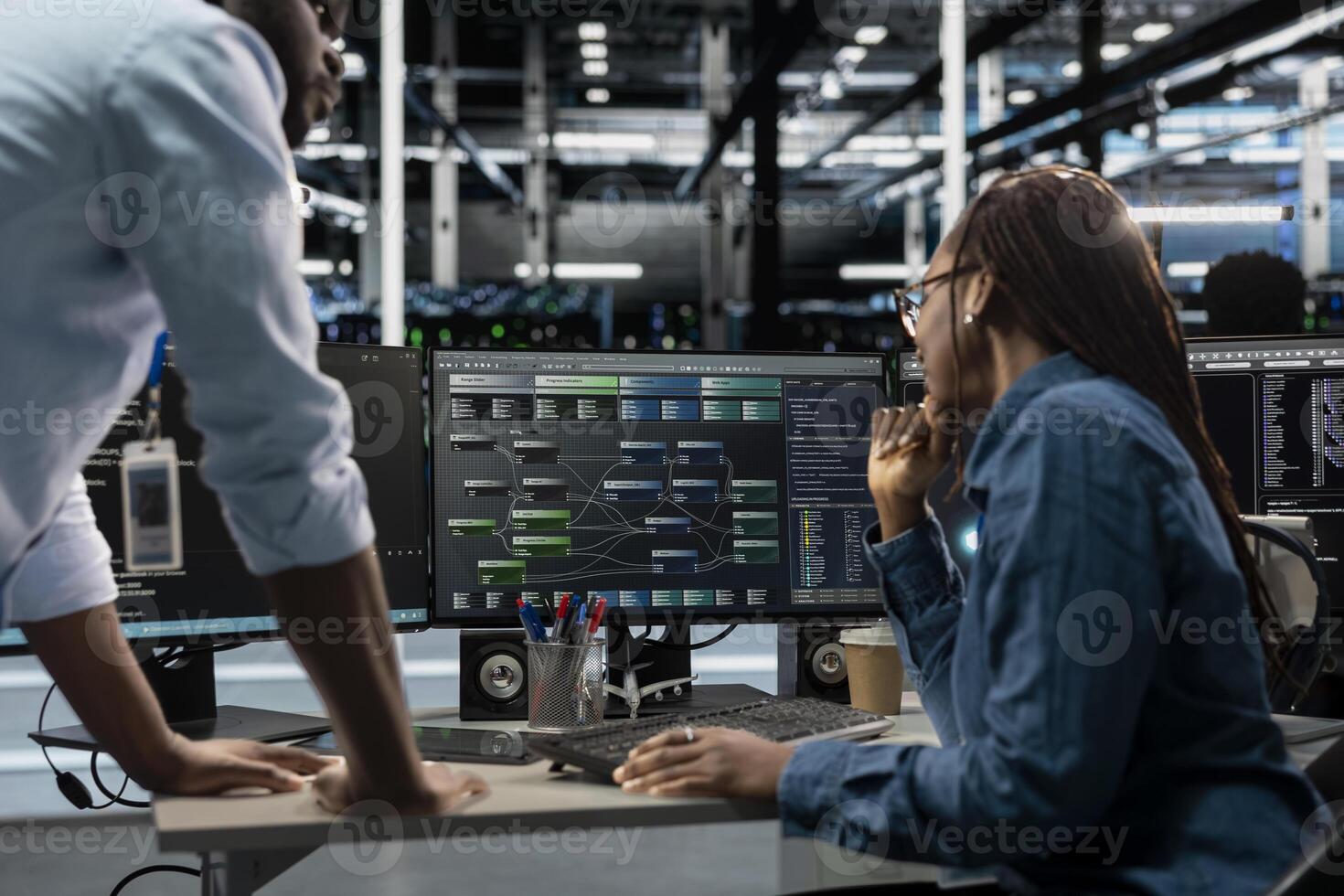 System administrators running node trees code and programming on PC, troubleshooting and upgrading server farm equipment designed to accommodate mainframes, networking racks and storage arrays photo