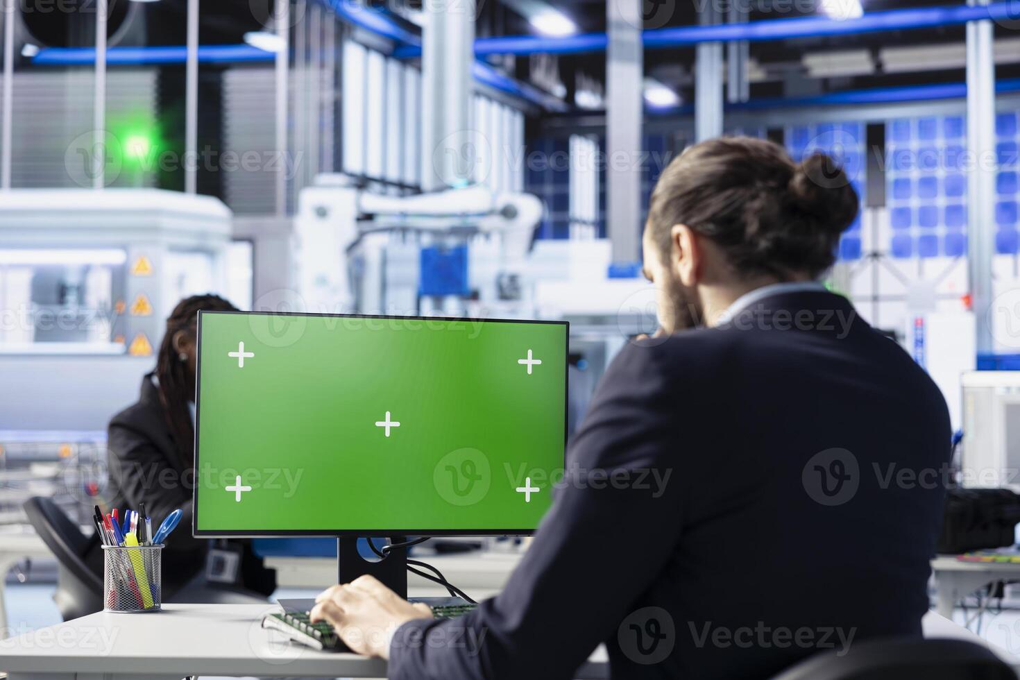 Technician in solar panel plant adjusting robotic machinery settings through green screen computer software. Photovoltaics factory employee diagnosing gear performance issues using chroma key PC photo