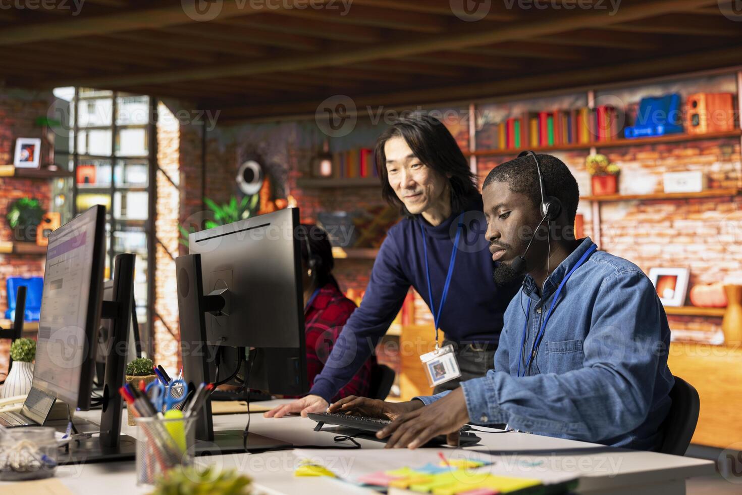 Upbeat call center senior manager evaluating new company intern performance by judging customers satisfaction. Happy Asian customer service department supervisor overseeing new worker onboarding photo