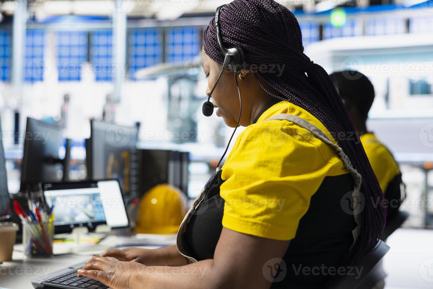 Black factory technician offers assistance from solar panel call center, managing help line requests for support and troubleshooting. Customer service assistant improves operations. photo