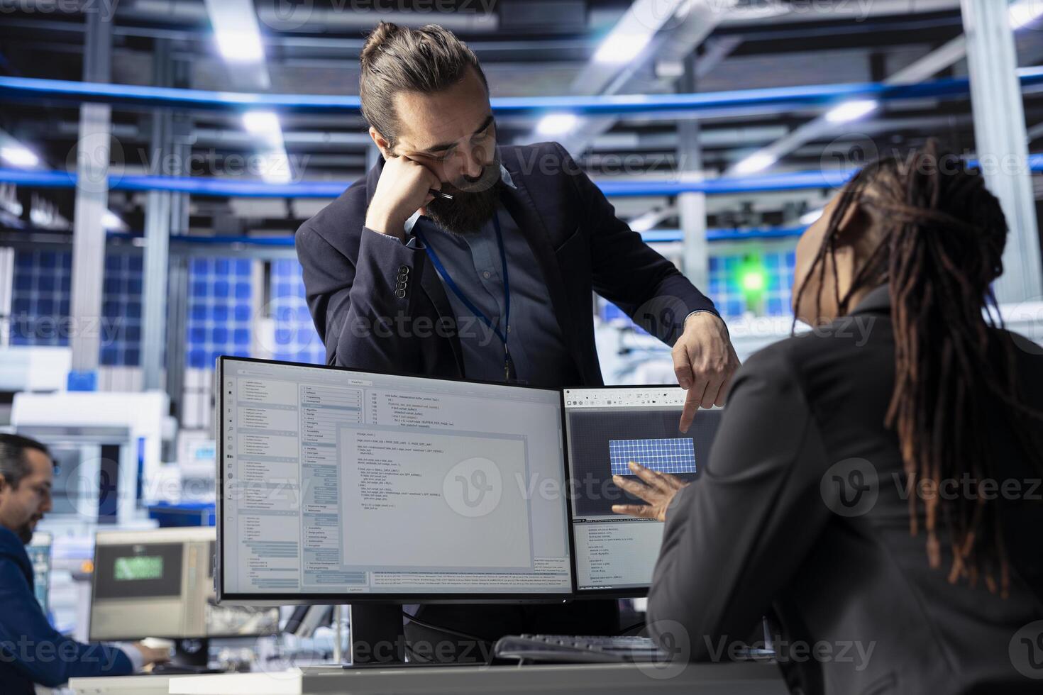 Solar panels plant manager checking up on programmer writing software to monitor machinery performance. Team leader and engineer creating solutions to integrate robotic systems with factory processes photo