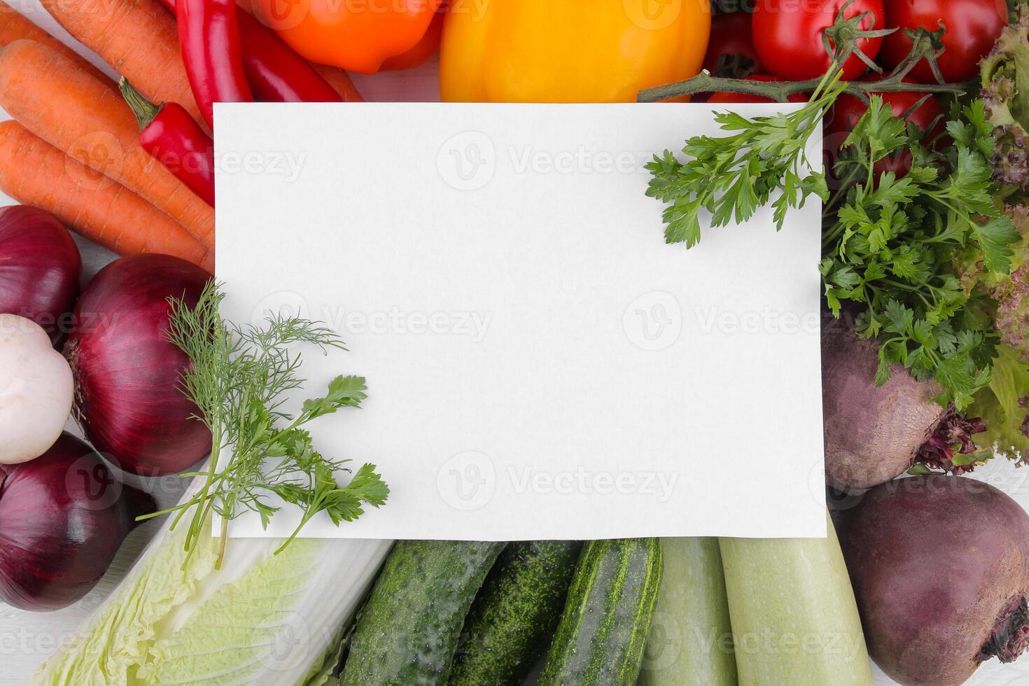 Many different vegetables include beets, cabbage, zucchini, carrots, tomatoes, peppers, onions, garlic, and cucumber with a blank form for recipes. top view photo