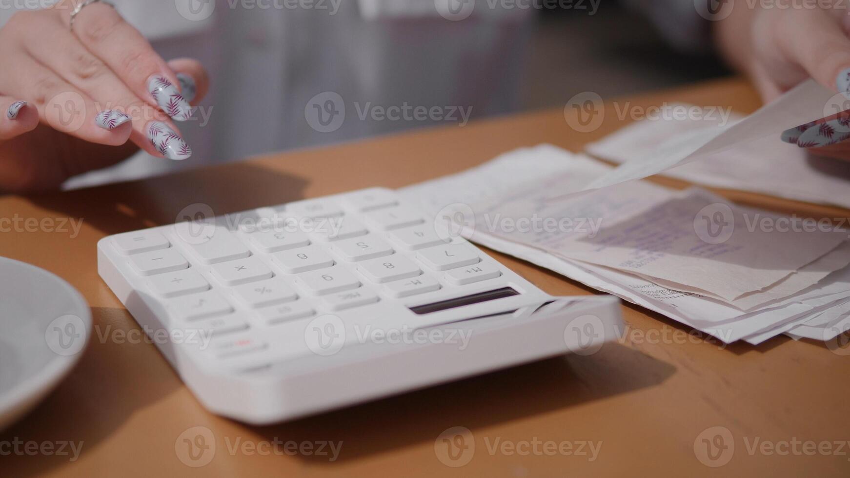A closeup view of hands skillfully using a calculator, with cash, documents, and files scattered on a wooden table photo