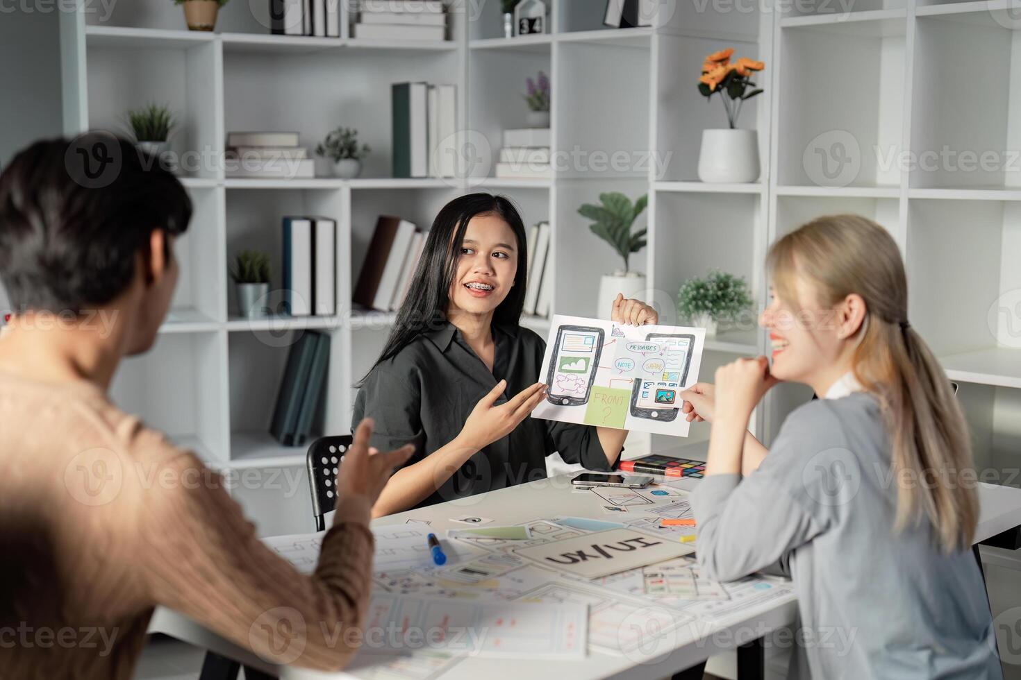 Team collaborating on UX UI presentation with prototypes and sketches. photo