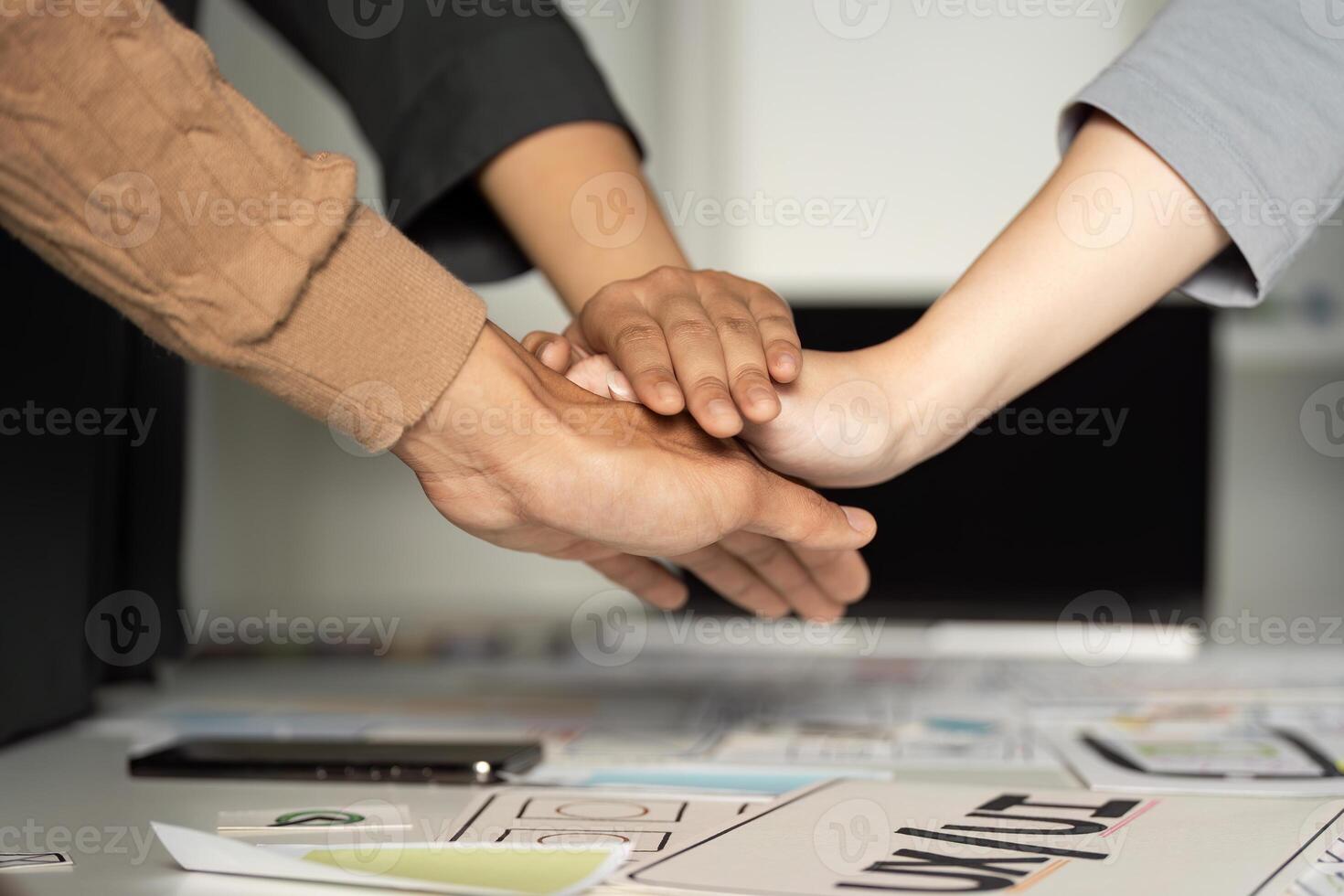 Collaborative Teamwork in UX UI Design Process with Hands Stacked Over Design Documents and Digital Devices photo