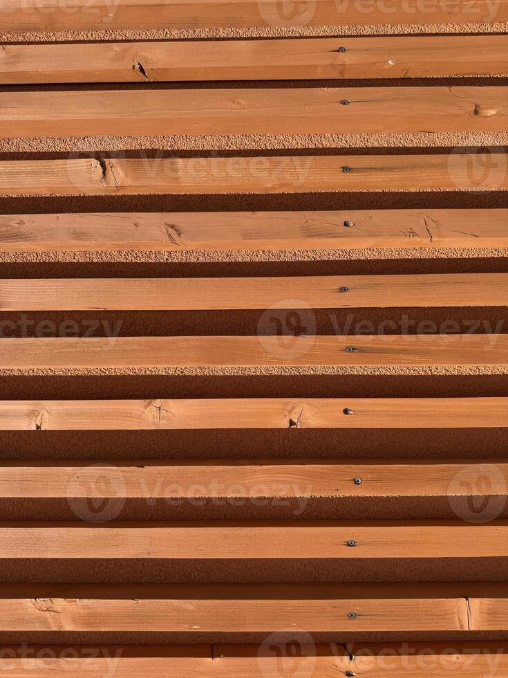 Symmetrical wooden slats in horizontal layout with terracotta tones texture and shadows architectural background modern building design surface structure geometry warm daylight pattern photo