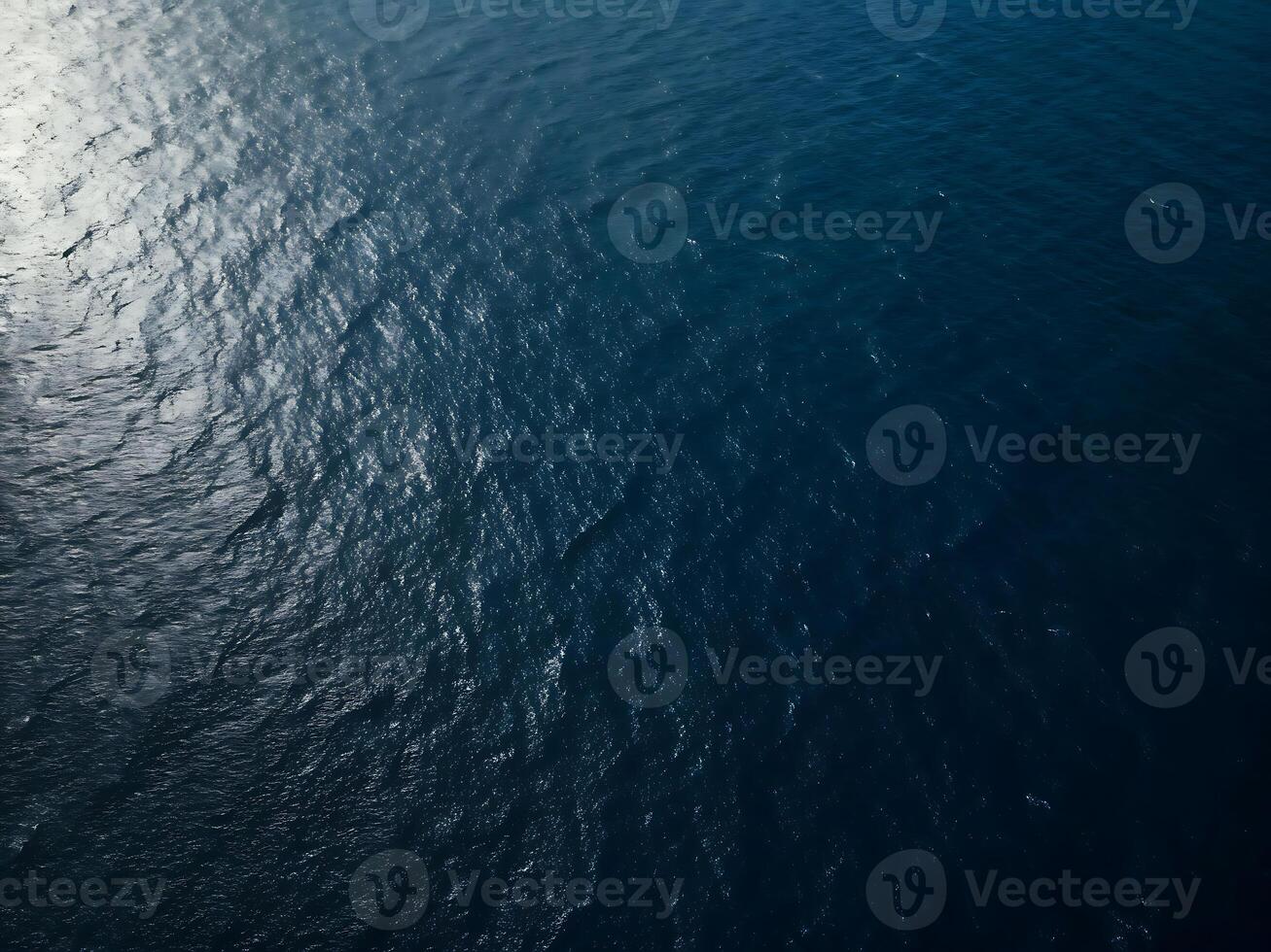 Photo of aerial view of the deep blue sea water surface with sun reflection, creating a mesmerizing texture and pattern, perfect for backgrounds and adding a touch of natures