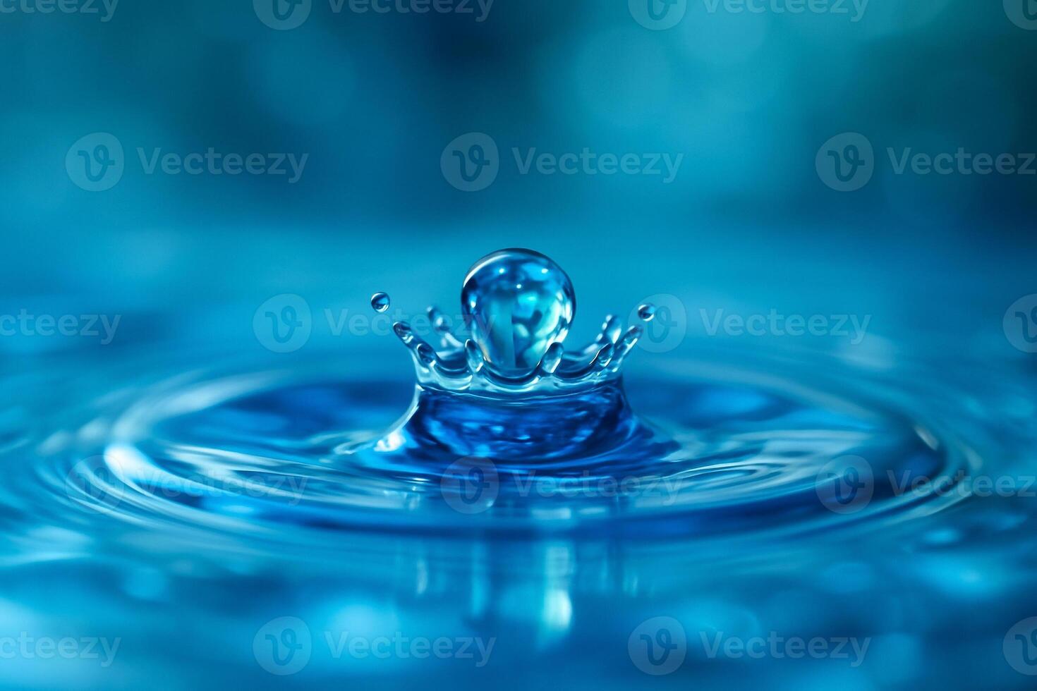 close up of a vivid blue water drop splashing into a clear liquid surface creating a crown shape with ripples and bubbles symbolizing purity freshness and elegance photo