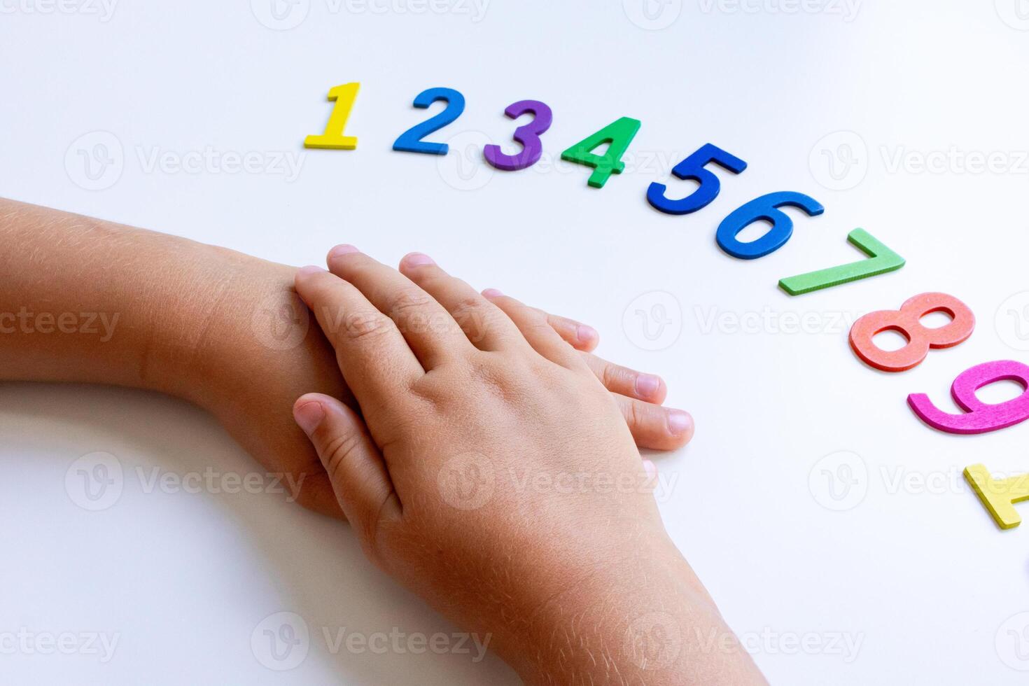 Child hands on table with colorful numbers 1 to 9 in sequence photo