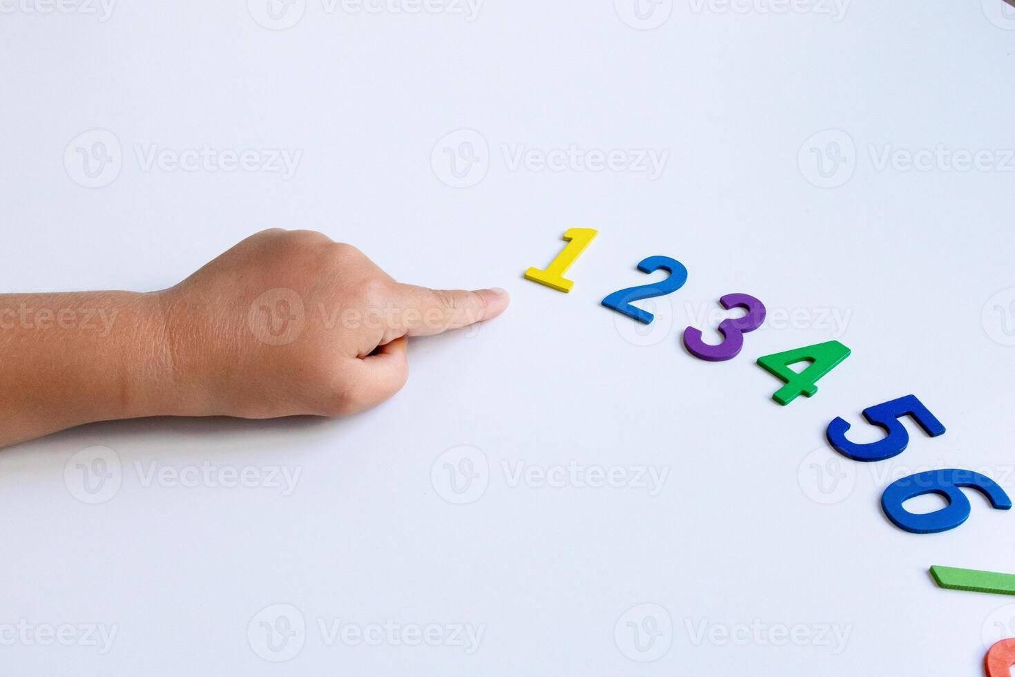Child learning numbers with colorful foam digits on white background photo