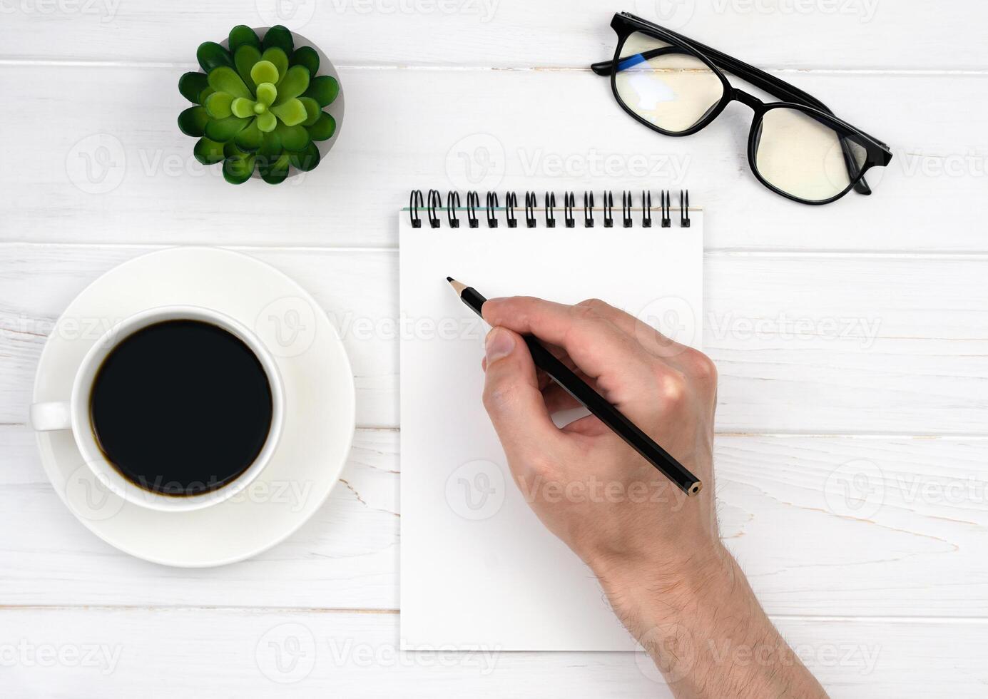 Man's hand makes notes in an empty notebook. Working table. Workplace. Top view. Flatlay. Selective focus. photo