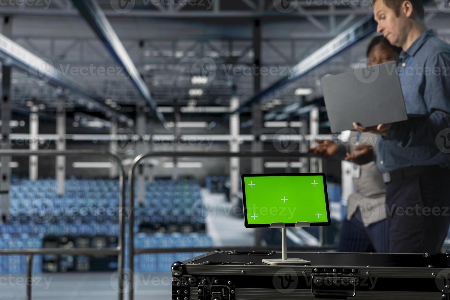 Server room colleagues managing large scale IT infrastructure using mockup device. Close up of green screen tablet in front of data center admins coordinating deployment of new server architectures photo