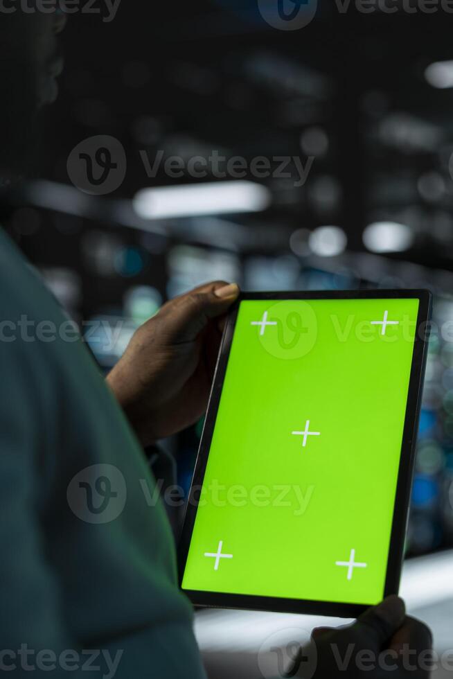 Close up of software developer in data center using green screen tablet to check for server performance issues. Server hub worker fixing malfunctions slowing down hardware using mockup device photo