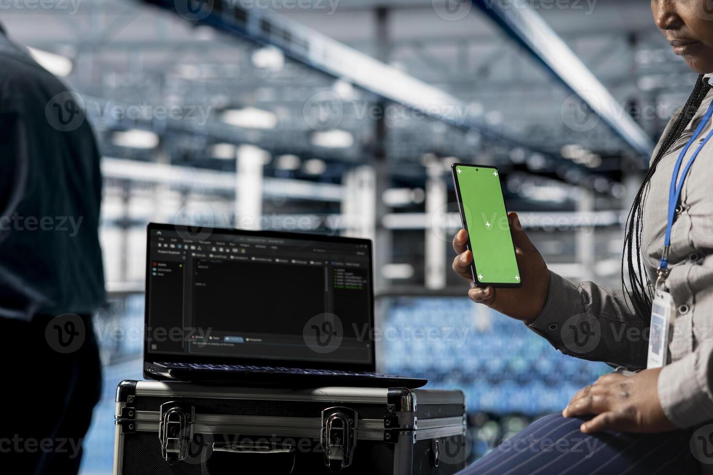 Close up of data center admin using green screen smartphone to relax while waiting for coding script to finish running. Server farm worker scrolls on chroma key phone, responding to texts during break photo