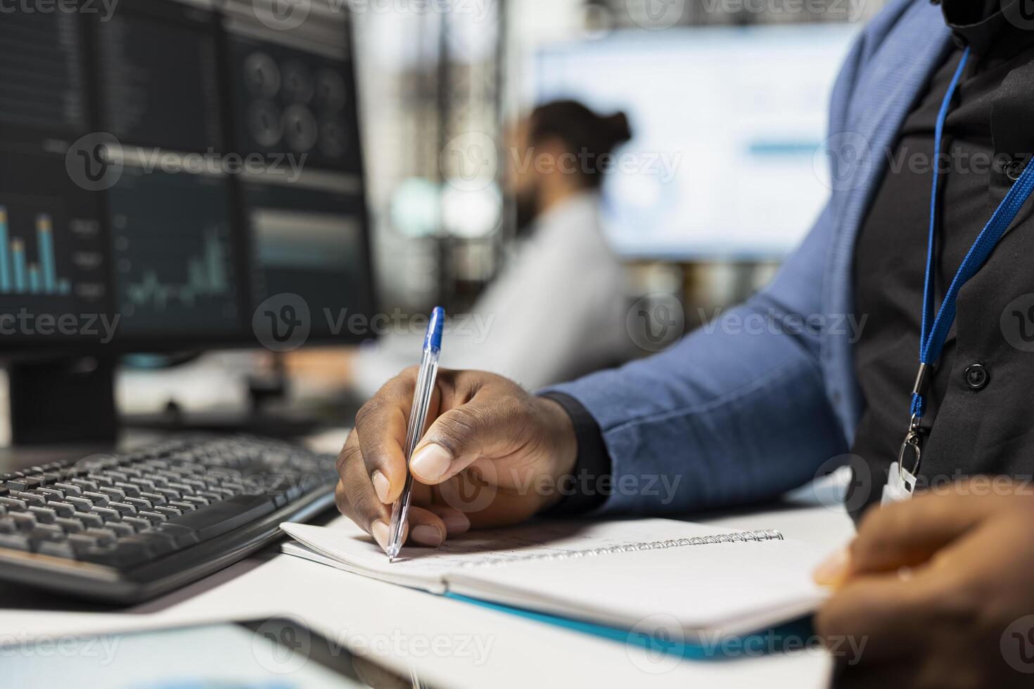 Close up of african american worker writes notes on textbook in the office, analyzing charts and graphs to align company objectives with strategy. Drive progress and measurable performance. photo