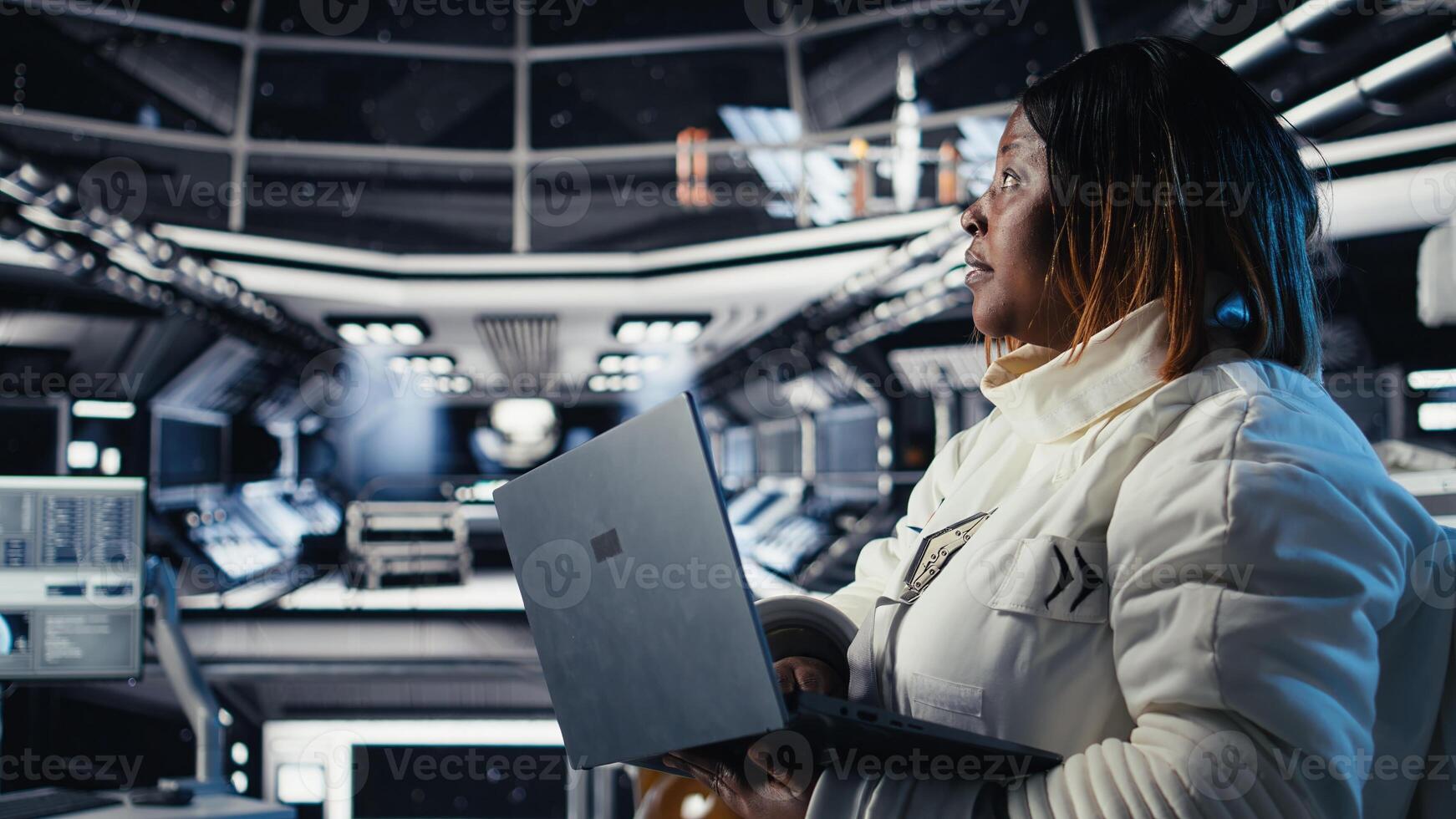 Astronaut returning from planet surface taking helmet off, talking with colleague using laptop to verify parameters. Cosmonaut finishing expedition chatting with coworker updating flight log photo