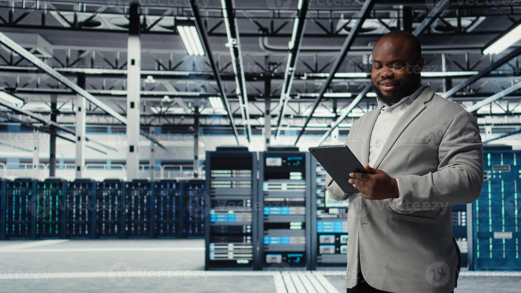 Cheerful data center programmer looking at code debugging tools running on tablet. Server farm IT professional typing on device touchscreen, writing script automating tasks, camera A photo