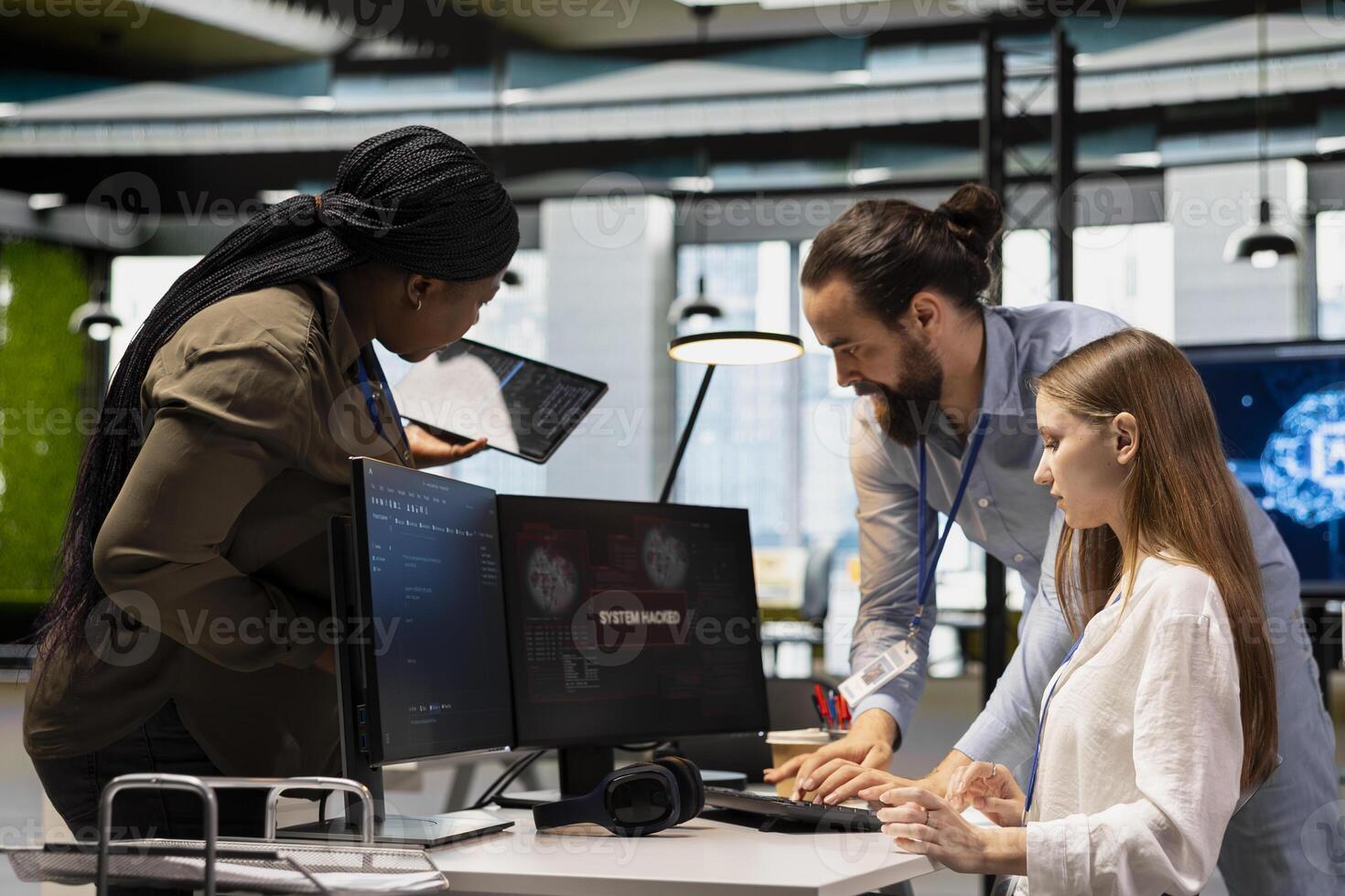 Young engineer in office requests help from IT experts detecting and blocking hacker intrusion. Female programmer assisted by staff members coordinating incident response for network attack photo