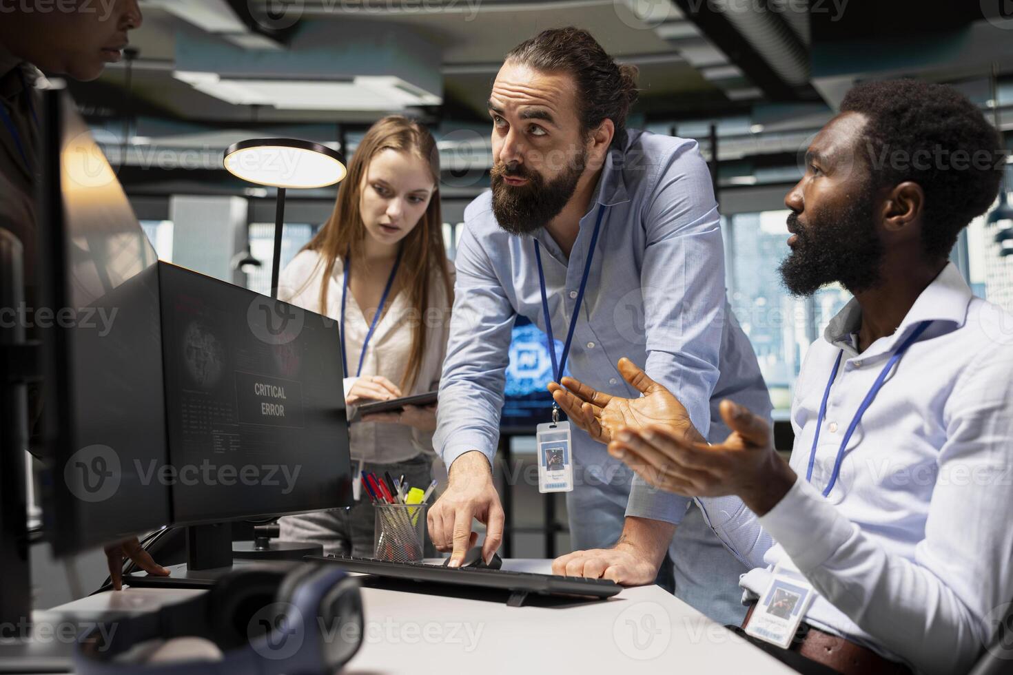 Team of programmers resolving critical error alert on screen in tech startup office, troubleshooting system warnings. IT staff members brainstorming fixes for office equipment failure photo