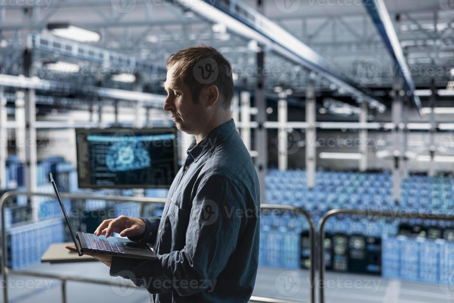 Engineer in AI data center managing software updates for system stability using laptop. Employee in server farm optimizing performance through artificial intelligence configurations photo