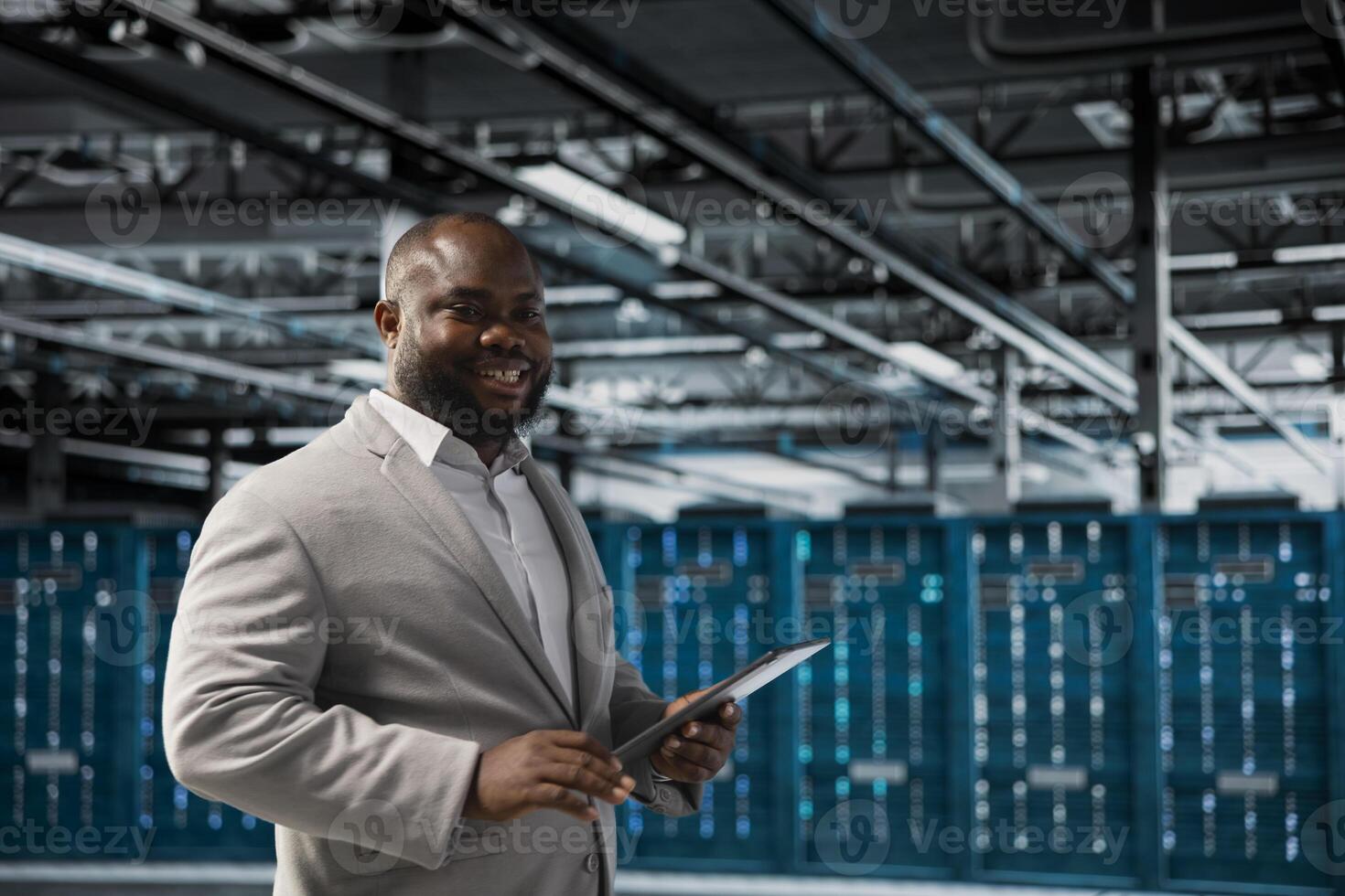 Happy technician in server hub checking recovery plan on tablet, monitoring energy consumption. Smiling data center employee using device, making sure sensors are functioning optimally photo