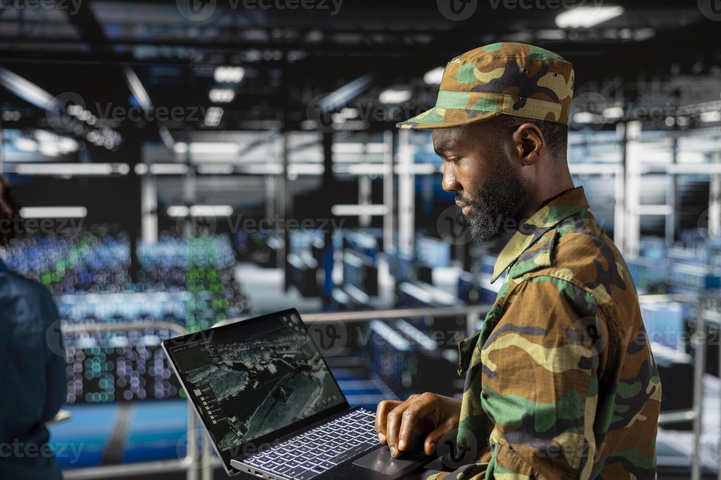 African american military officer in secure data center monitoring AI systems. Armed forces personnel in server farm ensuring stable infrastructure for deep learning defense operations. photo