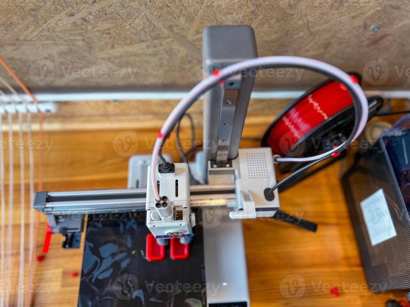 3d printer creating a prototype with red filament in a workshop photo
