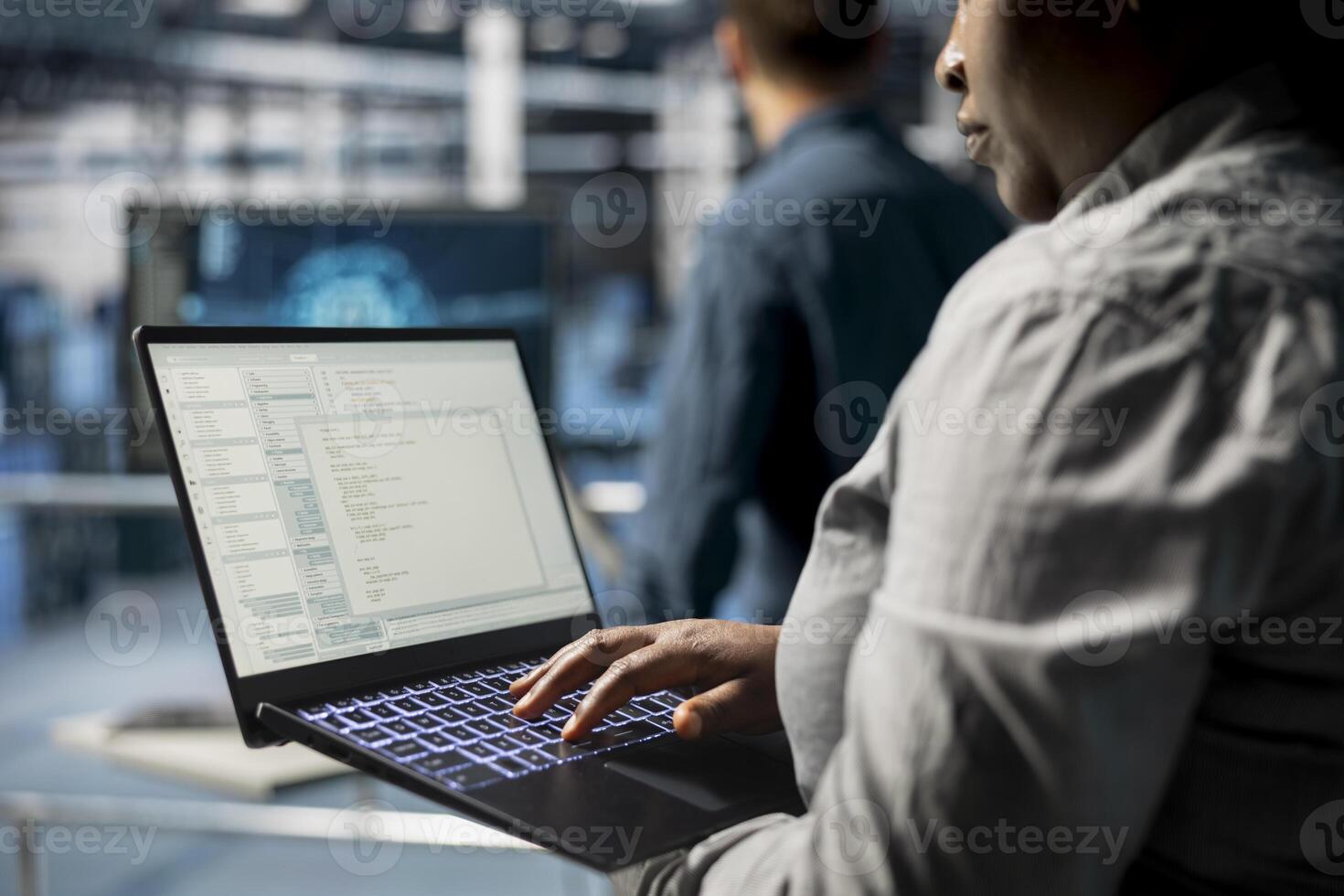 Close up of server room coworkers troubleshooting backend operations using software on laptop. Team of data center programmers compiling software patches to fix bugs using notebook photo